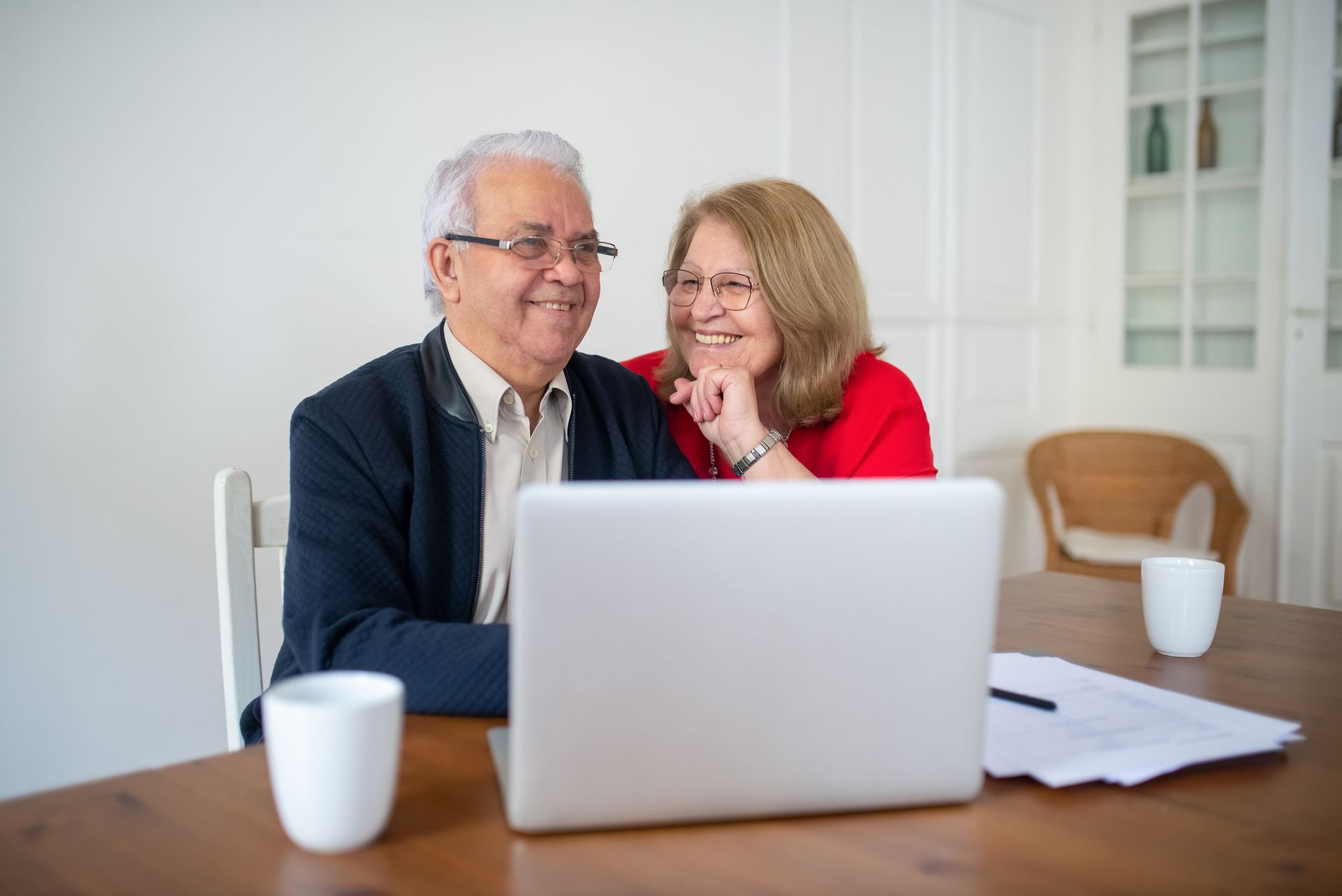 A happy mature couple smiling together while using a laptop at home